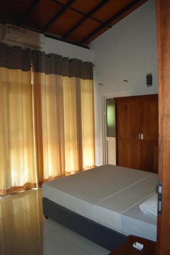a bedroom with a bed and a window with curtains at SaDev Lake Villa Bandaragama in Bandaragama