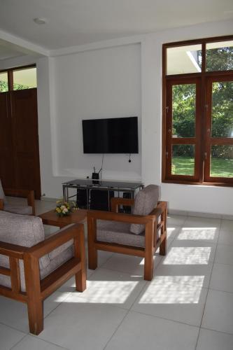 a living room with couches and a flat screen tv at SaDev Lake Villa Bandaragama in Bandaragama