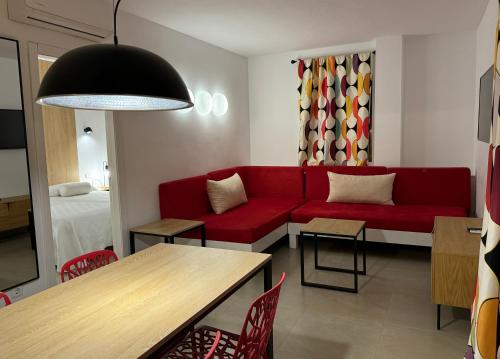 サンアントニオにあるAparthotel Boutique Poniente Playaのリビングルーム(赤いソファ、テーブル付)
