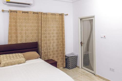 Stylish 2-bed Apartment Spintex في Kwedonu: غرفة نوم بسرير وباب زجاجي منزلق