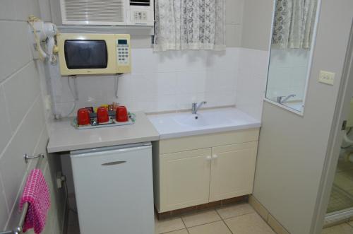 a small kitchen with a sink and a microwave at Welcome Home Motel Rockhampton in Rockhampton