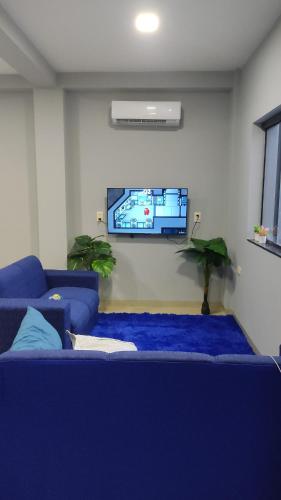 uma sala de estar com um sofá azul e uma televisão de ecrã plano em MEDPY HOSTEL em Pedro Juan Caballero