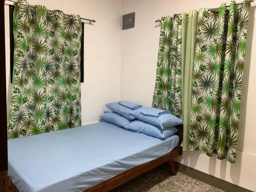 um pequeno quarto com uma cama com lençóis azuis em Altheos Place Romblon Cottage 1 em Romblon