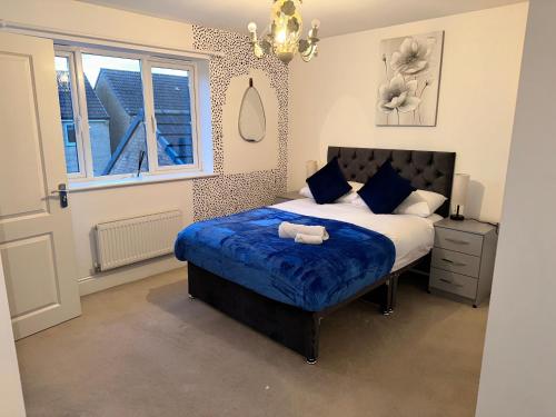 um quarto com uma cama com lençóis azuis e uma janela em Spacious & Relaxing Gem - Hot Tub - Games - Parking! em Peterborough