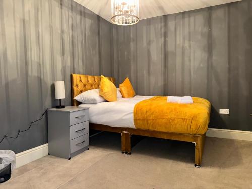 um quarto com uma cama grande e um cobertor amarelo em Spacious & Relaxing Gem - Hot Tub - Games - Parking! em Peterborough