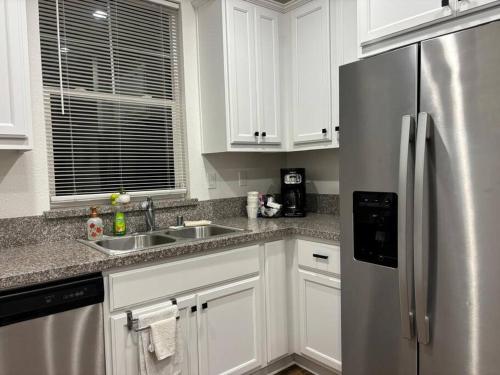a kitchen with white cabinets and a stainless steel refrigerator at Cozy Comforting Home in Merced