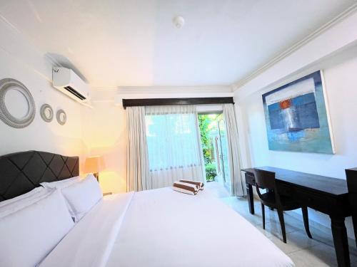 a bedroom with a white bed and a desk at Suite Hotel Apartment Legian by RCP in Seminyak