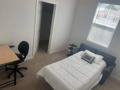 Schlafzimmer mit einem Bett, einem Schreibtisch und einem Fenster in der Unterkunft Cozy Comforting Home in Merced