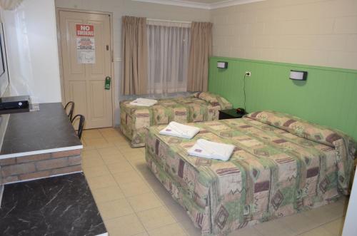 a hotel room with three beds and a door at Welcome Home Motel Rockhampton in Rockhampton