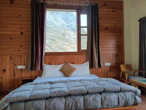Bett in einem Zimmer mit einem großen Fenster in der Unterkunft The Tranquil hotel in Chakrata