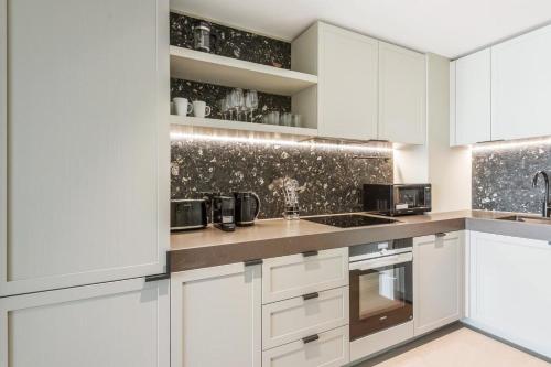 a white kitchen with white cabinets and appliances at Greenwich O2 in London