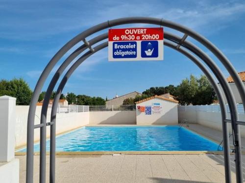 une piscine avec une arche au-dessus avec un panneau dans l'établissement Maison Cosy avec Piscine, Proche Plages et Commerces à La Tranche-sur-Mer - FR-1-22-194, à La Tranche-sur-Mer