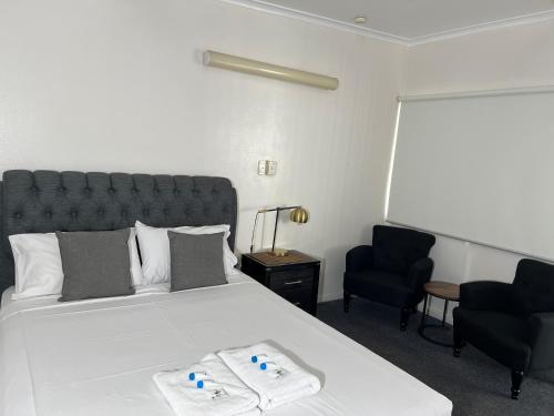 a bedroom with a large white bed and two chairs at Shell Motel (Pearly Shell Motel) in Bowen