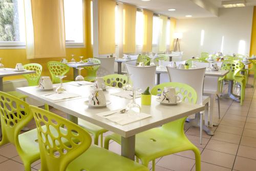 une salle à manger avec des tables blanches et des chaises jaunes dans l'établissement Villa Bellagio Euromedecine by Popinns, à Montpellier