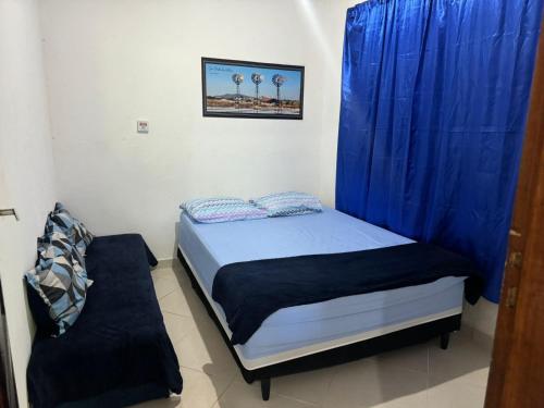 - une petite chambre avec un lit et un rideau bleu dans l'établissement hospedagemsaopedro apartamento com garagem a 13 km de Cabo frio 22 km de arraial do cabo, à São Pedro da Aldeia