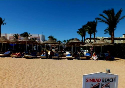 a beach with umbrellas and chairs and people on the sand at Sharm Hills Resort in Sharm El Sheikh