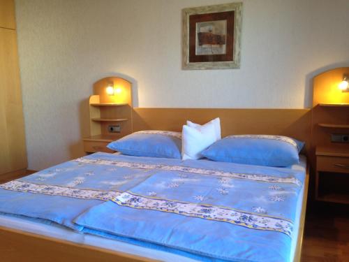 een slaapkamer met een groot bed met blauwe lakens en kussens bij Winzerhof Klua Hoada in Illmitz