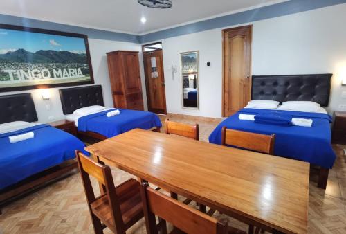 a room with two beds and a wooden table at Hotel Su Majestad in Tingo María