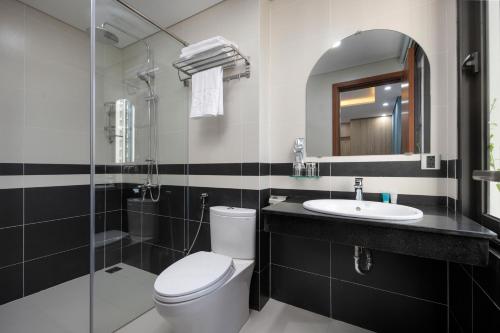 a bathroom with a toilet and a sink and a mirror at Hummer Hotel & Apartment Da Nang Beach in Danang