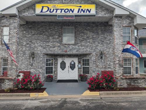 a building with a donation inn with a flag and flowers at Dutton Inn in Branson