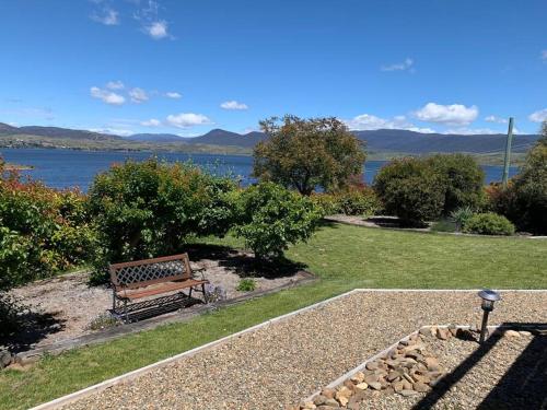 a bench sitting in a park next to a lake at Apartment minutes to Lake in Jindabyne
