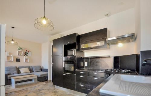 une cuisine avec des placards noirs et un canapé dans l'établissement Cozy Home In Villelongue De La S, à Villelongue-de-la-Salanque