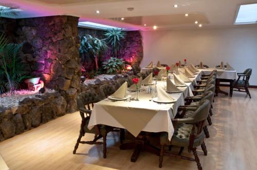a row of tables in a restaurant with a stone wall at Centro Internacional Apartahotel in Bogotá