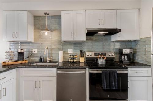 een keuken met witte kasten en een zwarte oven bij NEW! Comfy 1 Bedroom Flat I Hollywood Suites in Mount Clemens