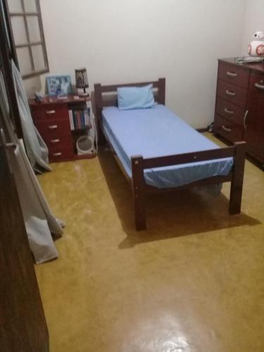 um quarto com uma cama com lençóis azuis e mobiliário em madeira em Casa Ampla em Passa Quatro