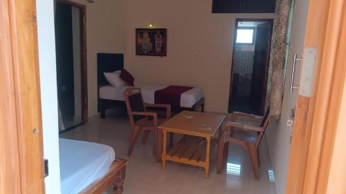 AthmA ArunA - Homestay Tiruvannamalai في تيروفانمالي: غرفة صغيرة بسرير وطاولة وكراسي