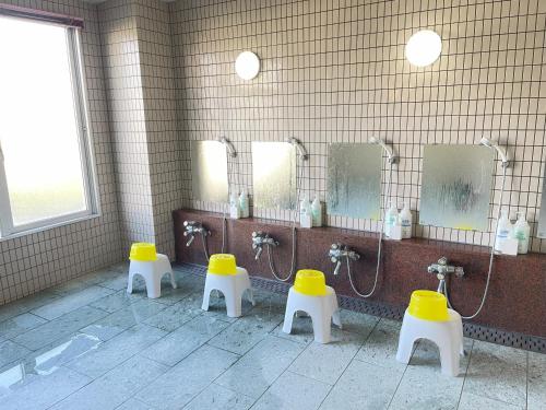 a public bathroom with three urinals with yellow seats at Felse Inn Gakusui in Hakuba