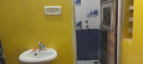 een gele badkamer met een wastafel en een douche bij Ayodhya home stay in Faizābād