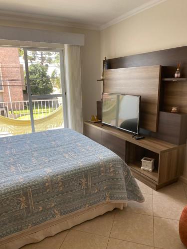 a bedroom with a bed and a flat screen tv at Lar doce lar da Lu in Curitiba