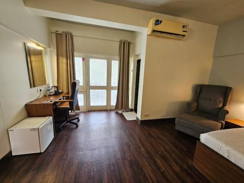 a hotel room with a desk and a bed and a chair at Andheri Sports Complex - VIP Guest House in Mumbai