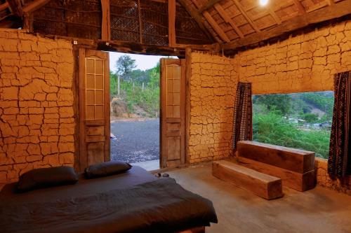 um quarto com uma cama e uma grande janela em Mơ Niê Farmstay & Cafe em Kon Von Kla