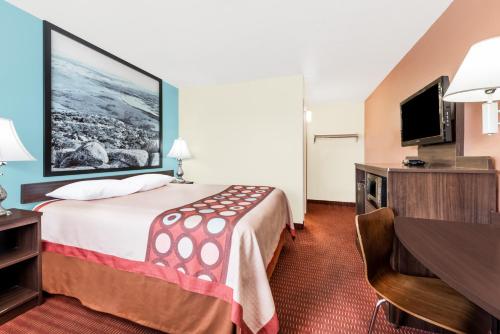 a hotel room with a bed and a flat screen tv at Super 8 by Wyndham Midwest City OK in Midwest City