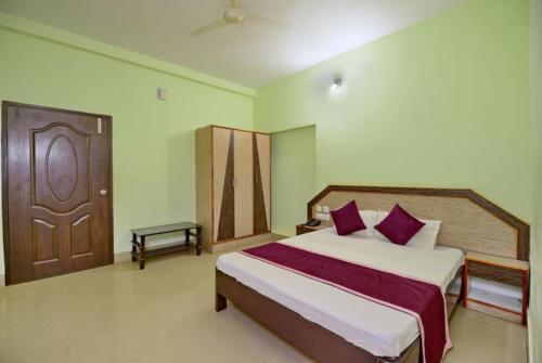 a bedroom with a large bed and a wooden door at Goroomgo Dittu Holiday inn puri-Near Nilandri Beach-Best Experince Ever in Puri