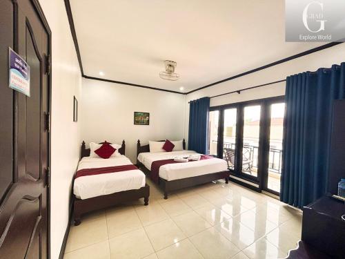 2 Betten in einem Zimmer mit Fenster in der Unterkunft Vang Vieng Central Hotel in Vang Vieng
