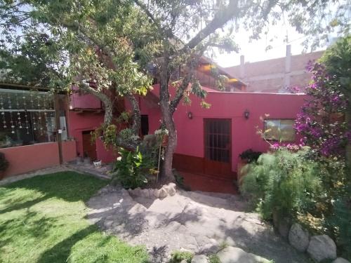 ein rosa Haus mit einem Baum im Hof in der Unterkunft Casa familiar Rumichaca in Urubamba