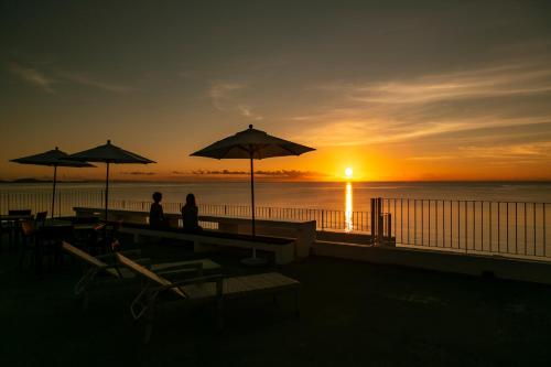two people sitting under umbrellas on the beach at sunset at Seven Colors Ishigakijima in Ishigaki Island
