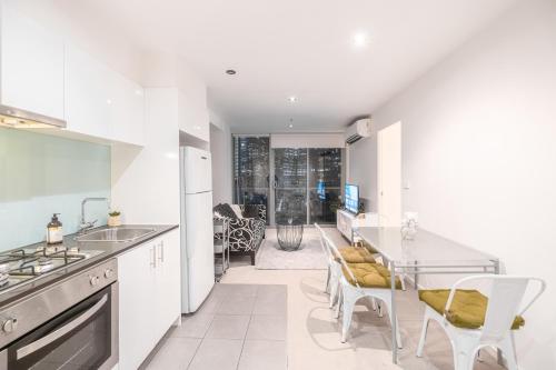 a kitchen with white cabinets and a table and chairs at 2br2ba Apartment Cbd Great Viewspoolgym in Melbourne