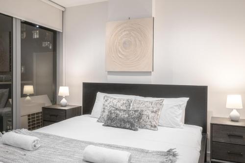 a bedroom with a large white bed with two lamps at 2br2ba Apartment Cbd Great Viewspoolgym in Melbourne