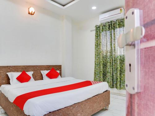 een slaapkamer met een bed met rode kussens en een raam bij OYO Hotel Shivansh in Bhopal