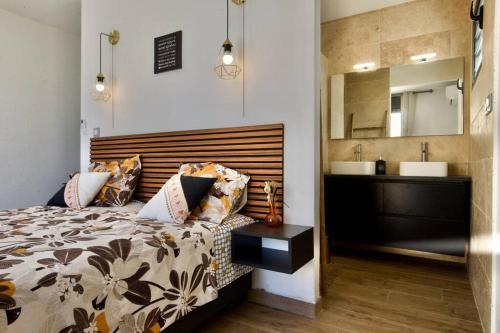 a bedroom with a bed and a sink and a mirror at Villa du Beau Vallon 2 classée 4 étoiles Jacuzzi privatif et piscine chauffée partagée in Saint-Benoît