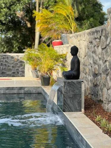 a statue of a boy sitting next to a fountain at Villa du Beau Vallon 2 classée 4 étoiles Jacuzzi privatif et piscine chauffée partagée in Saint-Benoît