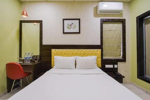 1 dormitorio con cama, escritorio y espejo en Goroomgo Royal Crown Puri, en Puri