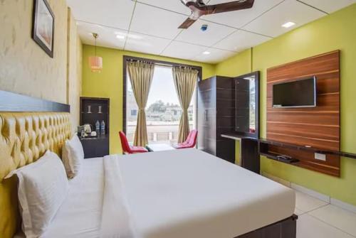 1 dormitorio con 1 cama blanca y TV en Goroomgo Royal Crown Puri, en Puri