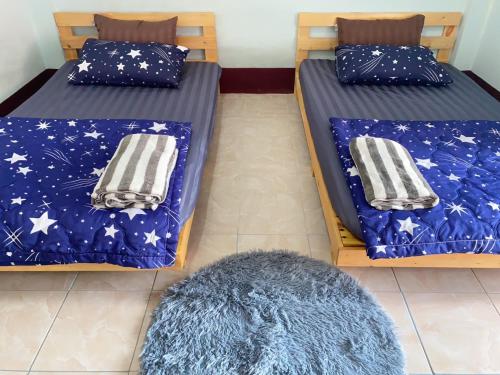 two twin beds in a room with a rug at CTM.INN (SISAKET)THAILAND 