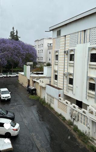 un parcheggio con auto parcheggiate di fronte a un edificio di شقق شهم المفروشه a Abha