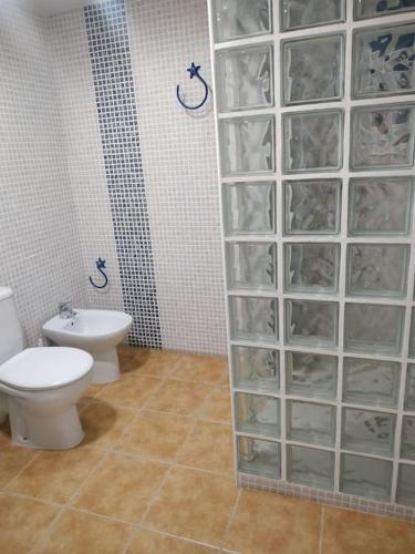 a bathroom with a toilet and a glass block wall at Desconexión y Relax in Mareny Blau
